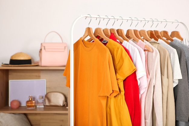 Fashionable clothes on hangers on a wardrobe rack in the background of the room