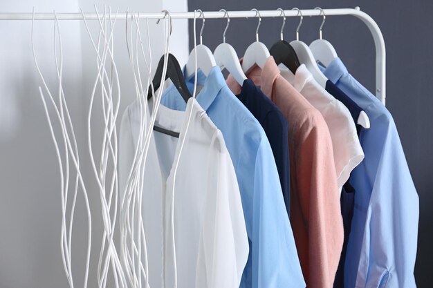 Fashionable clothes hanging on rack at room