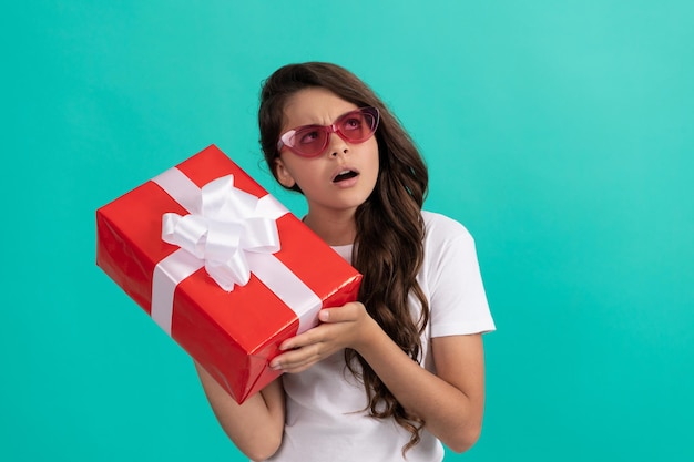 Fashionable curious kid in sunglasses hold gift box curiosity