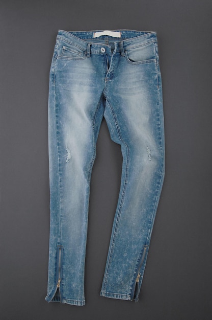 Fashionable denim pants on grey background top view