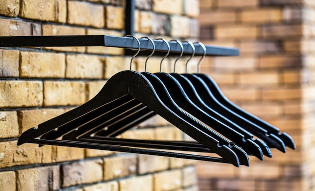 Fashionable different types of hanger. Wood hangers coat. Many wooden black hangers on a rod. Store concept, sale, design, empty hangers. Wooden coat hanger clothes.