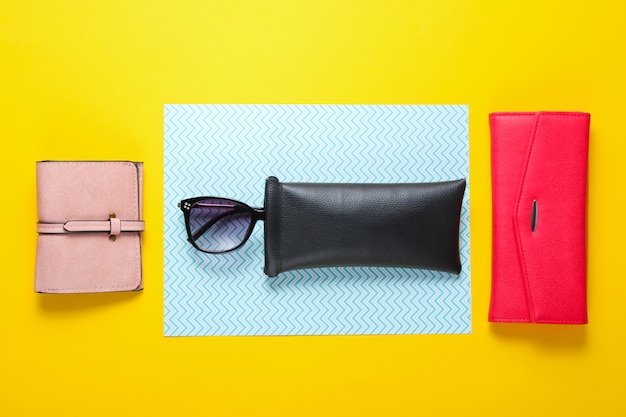 Fashionable female accessories. Trendy leather wallets, sunglasses in a protective case. Top view