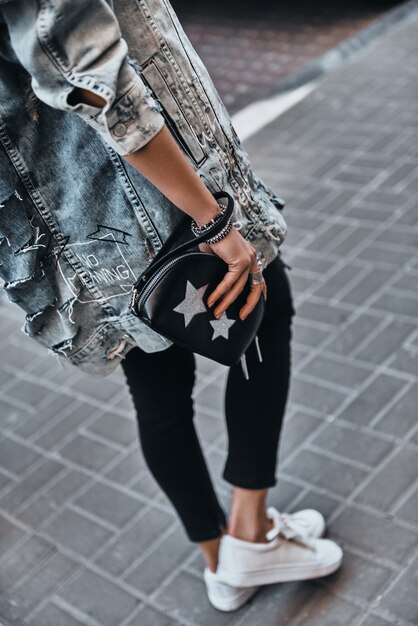 Fashionable girl. Close-up rear view of young woman carrying a purse 