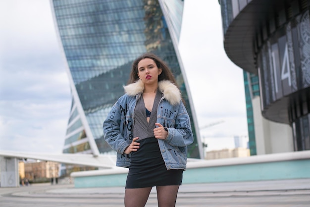 A fashionable girl with a wavy hairstyle and red lips poses on the street