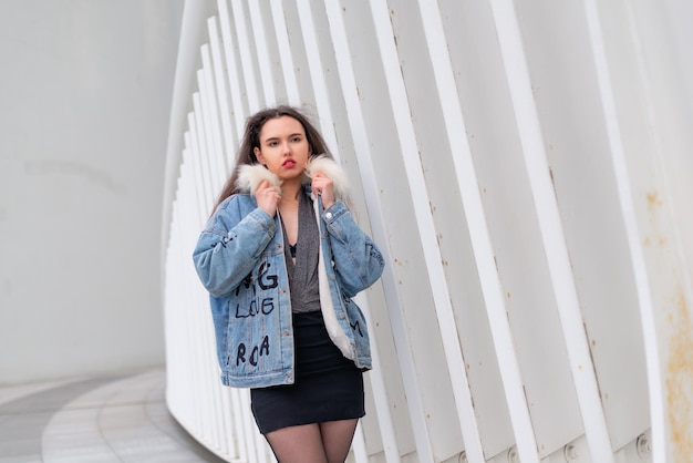 A fashionable girl with a wavy hairstyle and red lips poses on the street