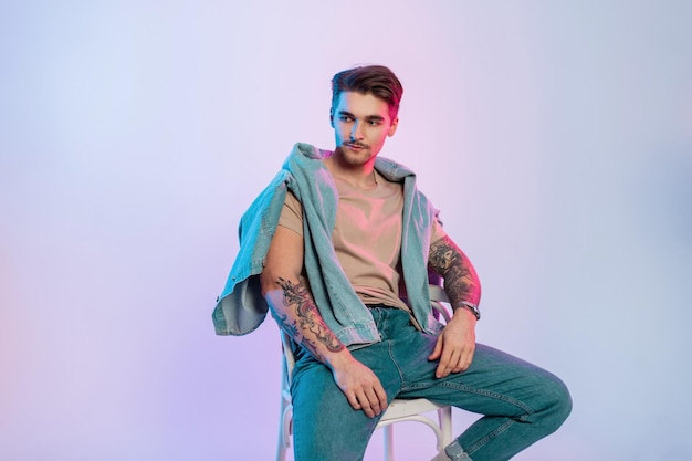 Fashionable handsome man with jeans clothes sitting in the studio