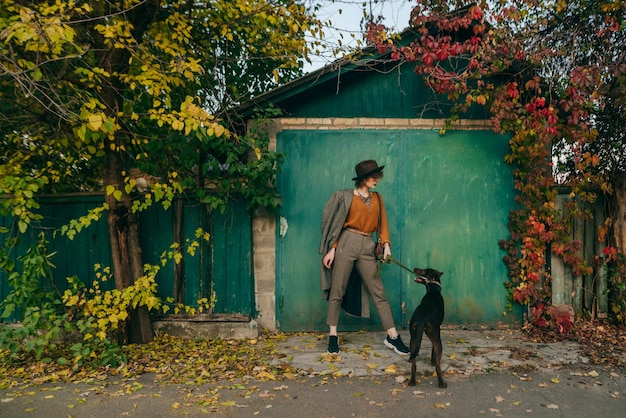 Fashionable lady posing with a dog against the background of a green wall of country cottage