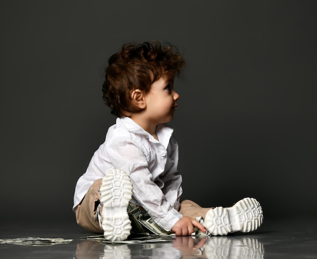 Fashionable little baby boss and money Little toddler kid playing banknote cash counting Isolated portrait isolated shot on gray studio background Allowance for children and finance