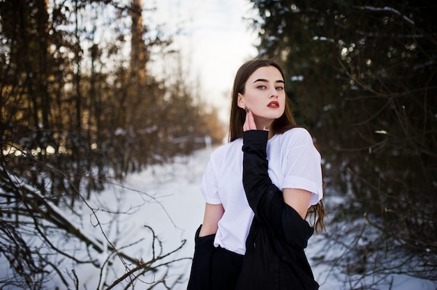 Fashionable long legs brunette model in long black cloak posed outdoor at winter day.