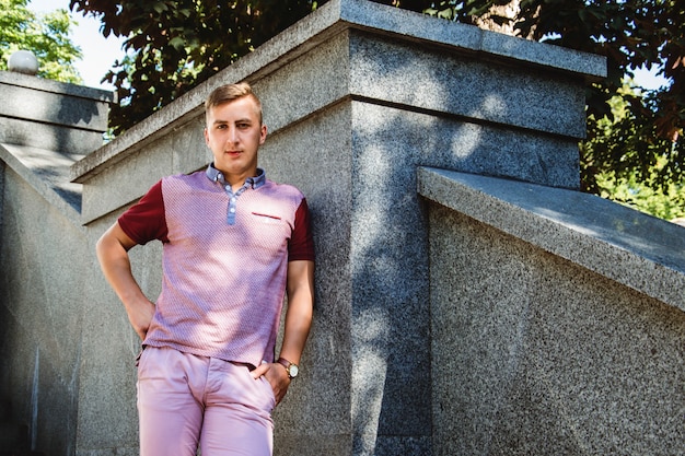 Fashionable man in beige trousers against stone wall