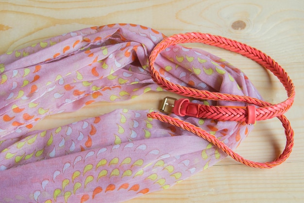 Fashionable pink accessories on wooden background scarf belt