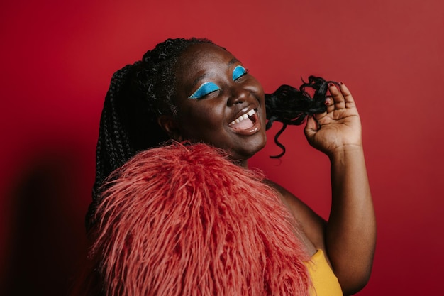 Fashionable plus size African woman with beautiful makeup touching hair and smiling