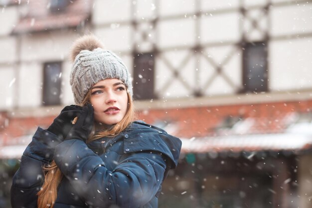 Fashionable redhead woman walking at the holiday winter fair during snowfall. Space for text