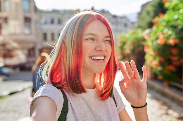 Fashionable teenage girl looks at webcam and talks on city street