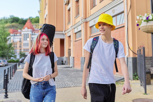 Fashionable teenagers couple guy and girl walking together along city street