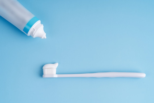 Fashionable toothbrush with soft bristles. Popular toothbrushes. Hygiene trends. Top view with a tube of toothpaste applying on brush.