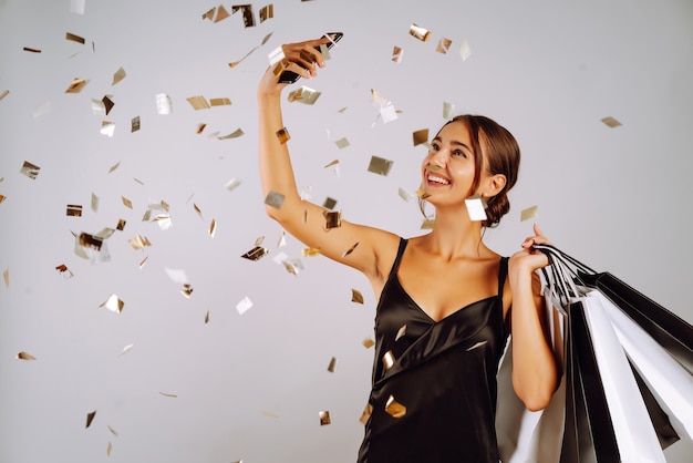 Fashionable woman in black dress holding shopping bags