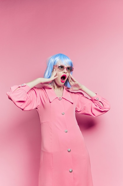 Fashionable woman in blue wig pink dress red lips isolated background