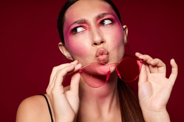 Fashionable woman pink glasses bright makeup posing black jersey pink background unaltered