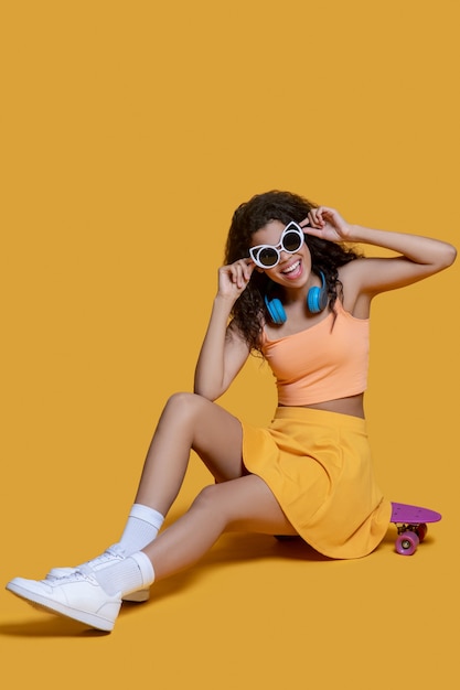 Fashionista. Pretty dark-haired young girl with a skateboard and sunglasses