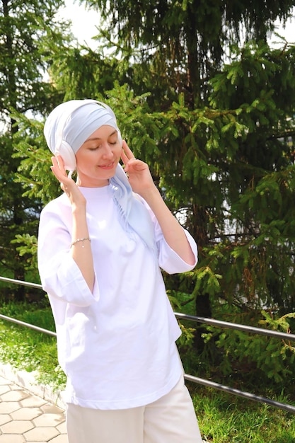 A fasion modren muslim girl is listening to music in headphones outdoor