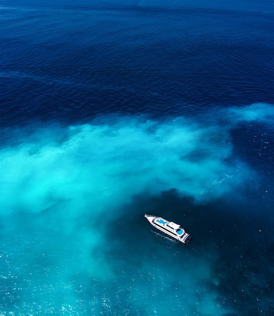 Fast boat at the sea in Bali Indonesia Aerial view of luxury floating boat on transparent blue water at sunny day Summer seascape from air Top view from drone Travel image