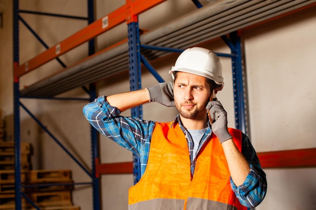 Fast delivery service. Warehouse worker in protective helmet talking on the phone.