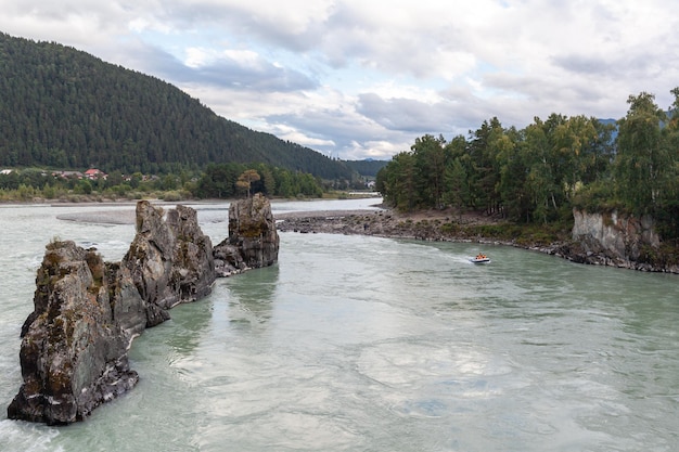 A fast-flowing wide and full-flowing Big mountain river. Large rocks stick out of the water.