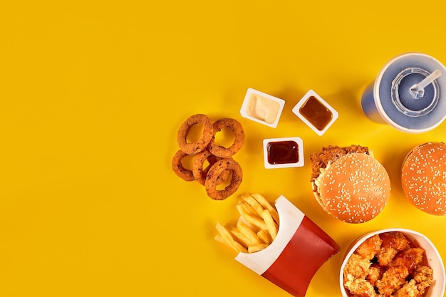 Fast food dish top view French fries hamburger mayonnaise and ketchup sauces on yellow background