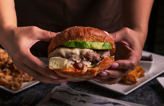 Fast food people and unhealthy eating concept close up of woman hands with burger