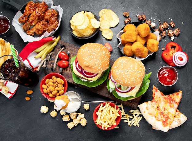 Fast food and unhealthy eating concept close up of fast food snacks and cola drink on a dark background top view