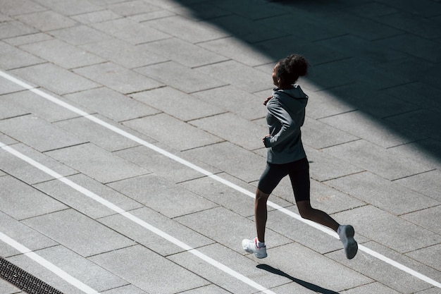 Fast runner Young african american woman in sportive clothes have workout outdoors at daytime