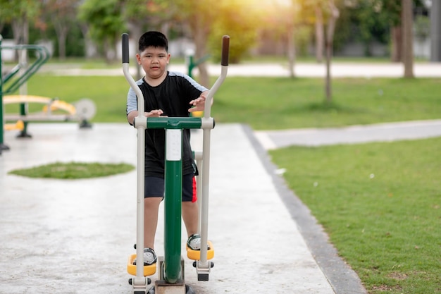 Fat boy trains on fitness equipment in the park