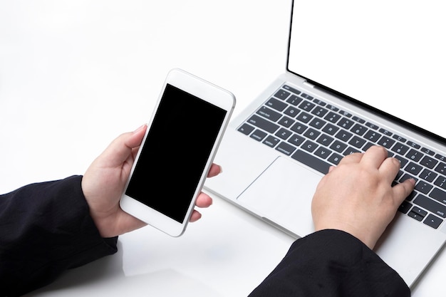 Fat businesswoman's hand holding smartphone and using laptop to working her job on white table