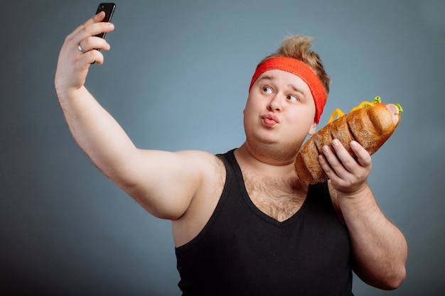 Photo fat man with sandwich in hand makes selfie