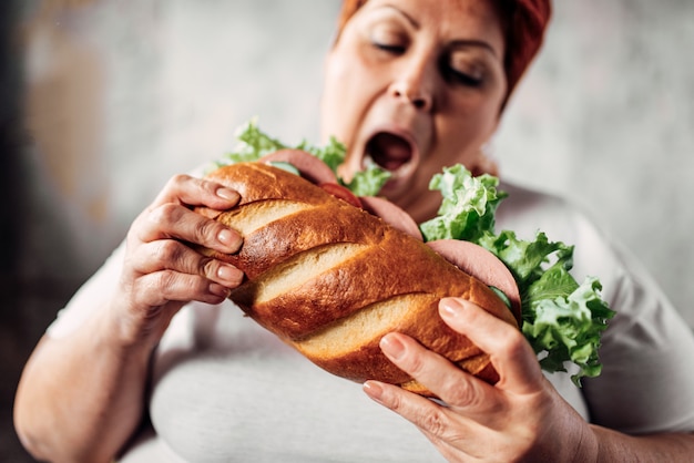 Fat woman eats sandwich, overweight and bulimic