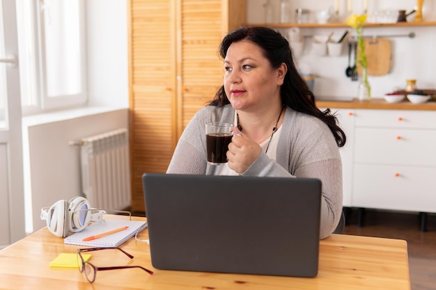 A fat woman is sitting at a table with a laptop