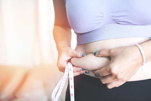 Fat woman measuring fat woman fat belly chubby paunchy sport recreation health care lose belly fat concept woman holding excessive belly with measure tape