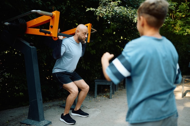 Father and boy on exercise machine, sport training