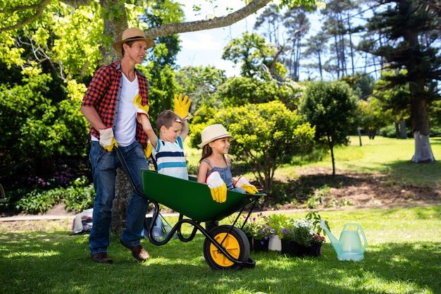 Father carrying his son and daughter in a wheelbarrow