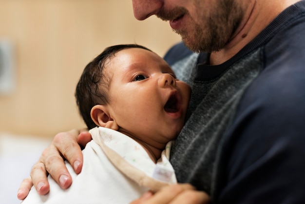 A father carrying a newborn baby