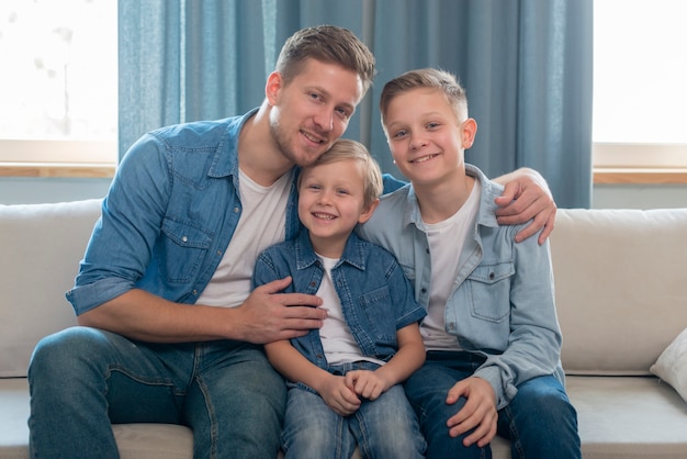 Father and cute brothers sitting on the couch