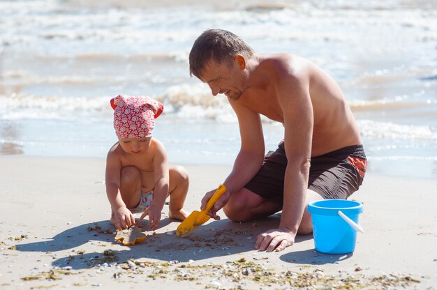 Father and daughter on beach playing and building sand castle