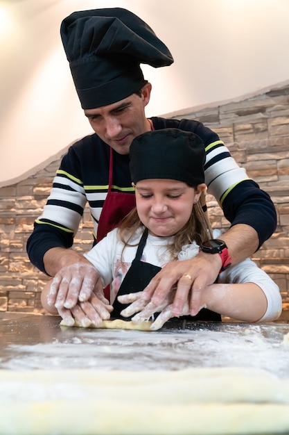 Father and daughter cooking a pastry together in chef's costumes