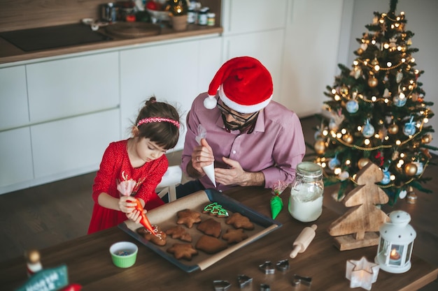 Father and daughter decorating gingerbread cookies