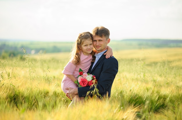 Father and daughter in a green wheat field