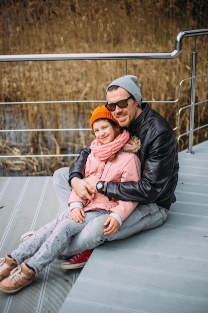 Father and daughter hug each other have fun and laugh outside in autumn