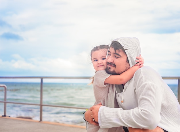 Father and daughter hugs on a walk with sea views