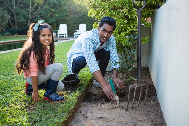 Father and daughter planting a tree in garden at backyard