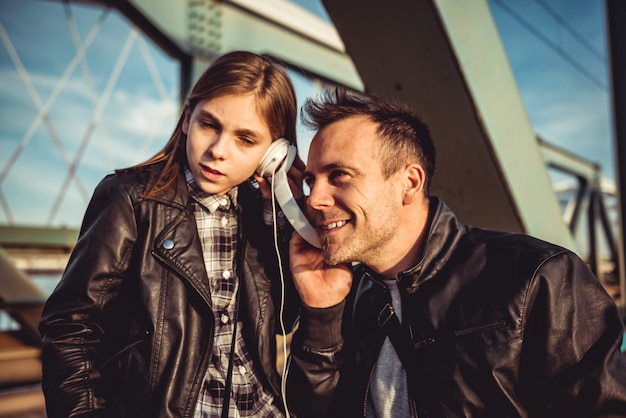 Father and daughter relaxing on bridge and listening music